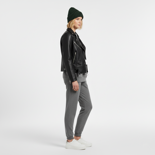 Side view of a woman in a black faux leather biker jacket with grey joggers