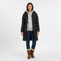 Woman wearing a long black quilted hooded winter coat, worn open over a grey hoodie, front view